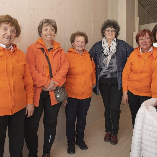 Fotografija iz otvoritve – 15 Skupina žensk v oranžni opravi in gospa v sivo modri jakni